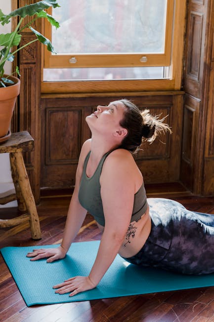 Person doing a gentle stretch on a yoga mat by a window.